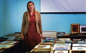 Caroline Fernald standing in front of a desk with art at the Millicent Rogers Museum.